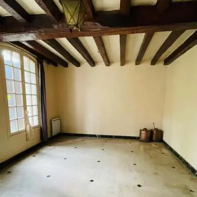 An empty room with exposed ceiling beams in the family home