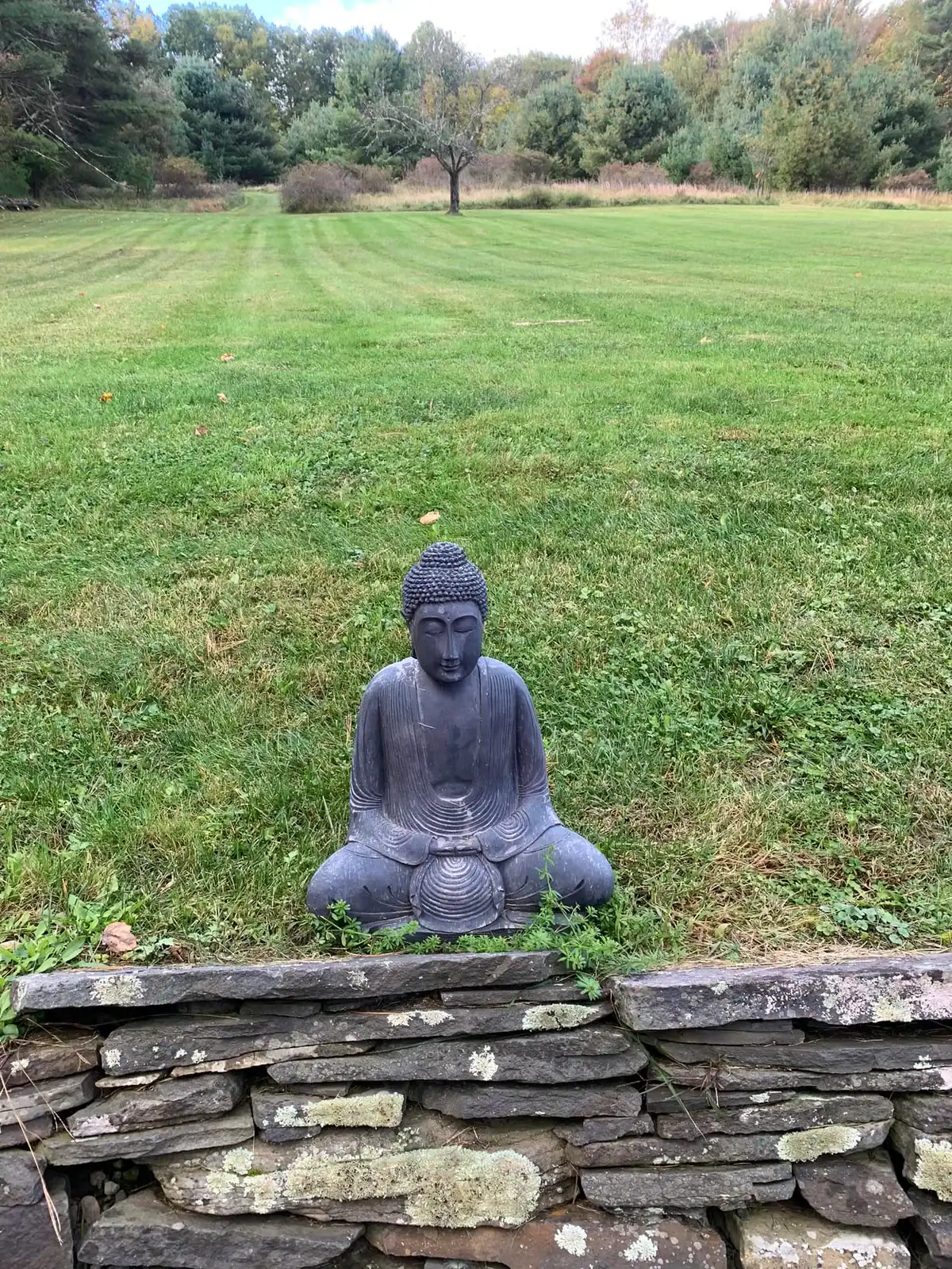 A Buddha statue facing a wide green lawn in Kerhonkson