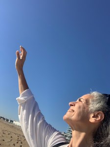 Anne Newgarden standing at the shoreline with one arm raised