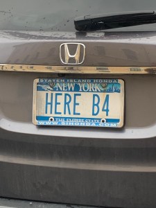 New York license plate reading “HERE B4”