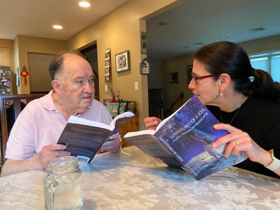A woman and an older man reading Adventures of a Soul at a table