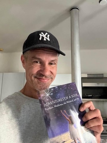 A man in a Yankees cap holding Adventures of a Soul