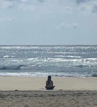 A person meditating on the beach