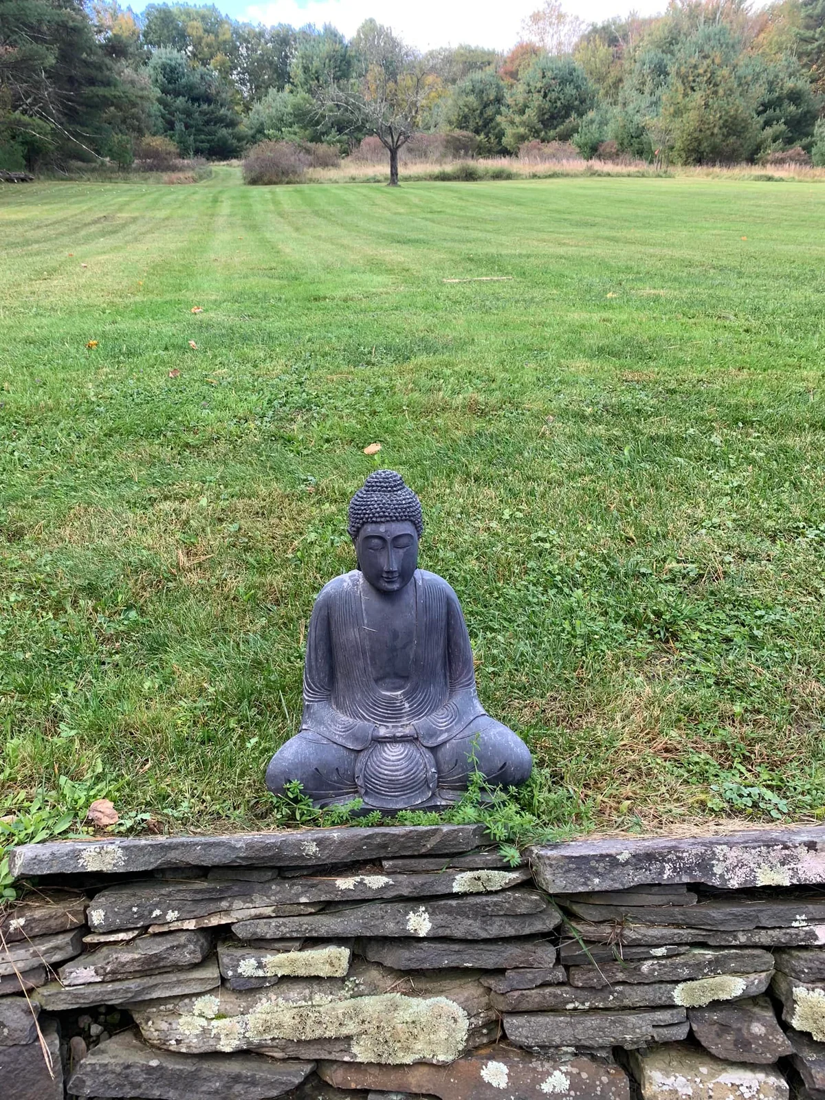 A Buddha statue facing a wide green lawn in Kerhonkson