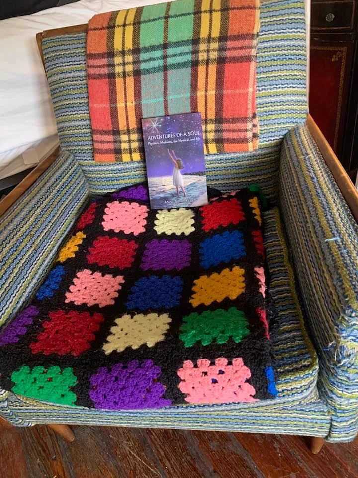 The threadbare armchair draped with a colorful crocheted blanket