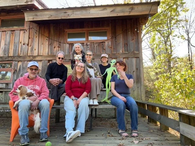 Members of Anne Newgarden's Power of Eight group seated on a cabin porch in Kerhonkson