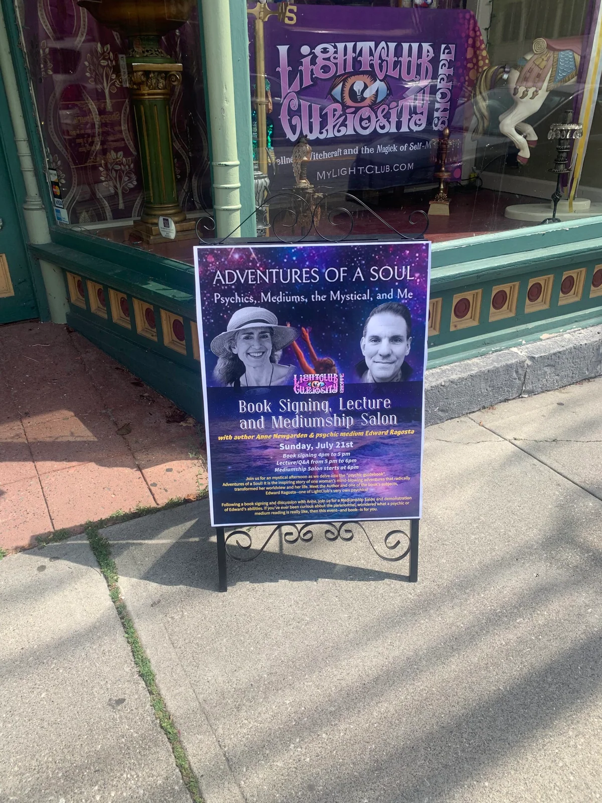 Sidewalk sign outside LightClub advertising Anne Newgarden and Edward Ragosta's July 21 book signing and mediumship salon